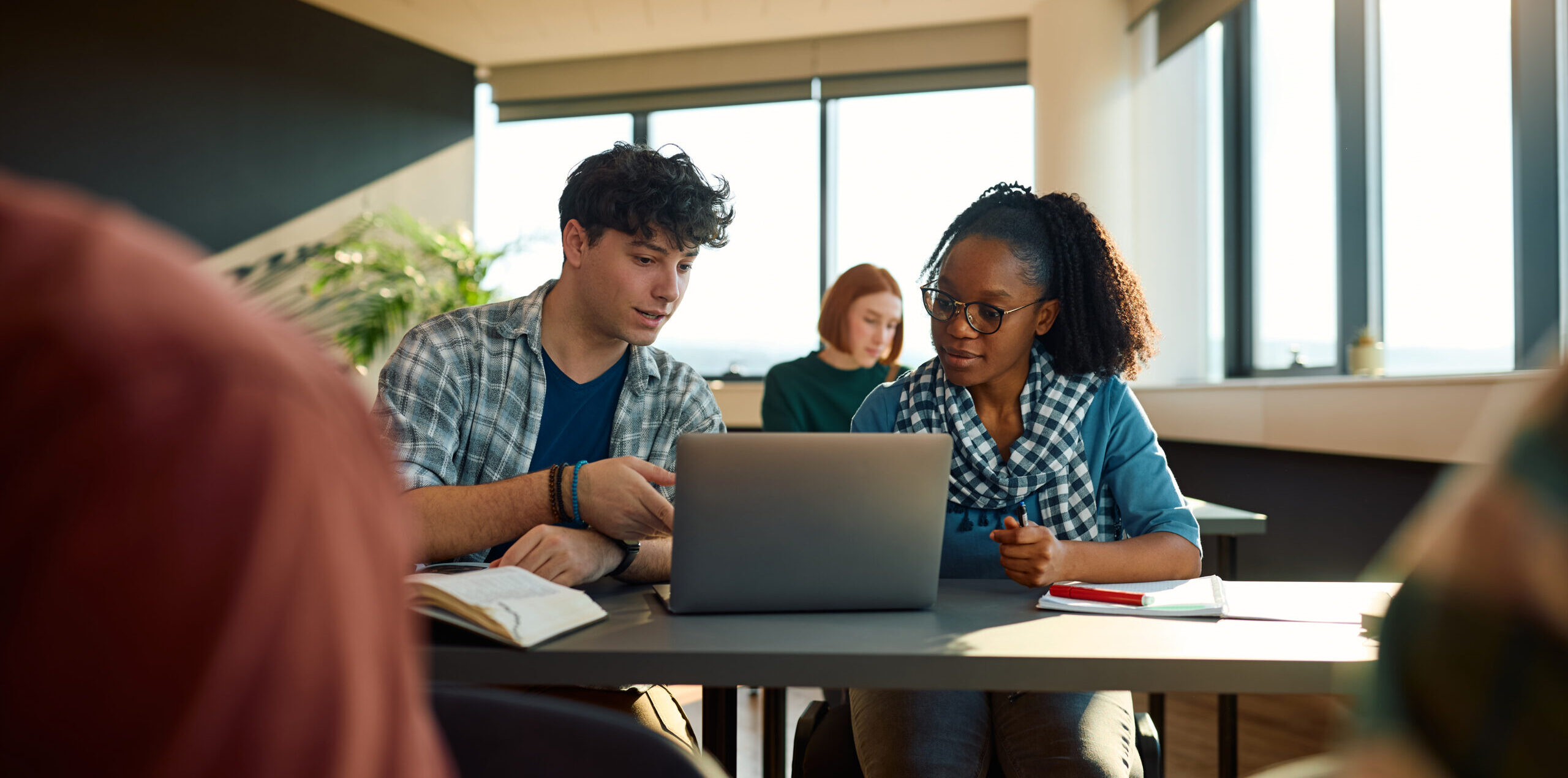 Multiracial students e-learning over a laptop at university classroom.